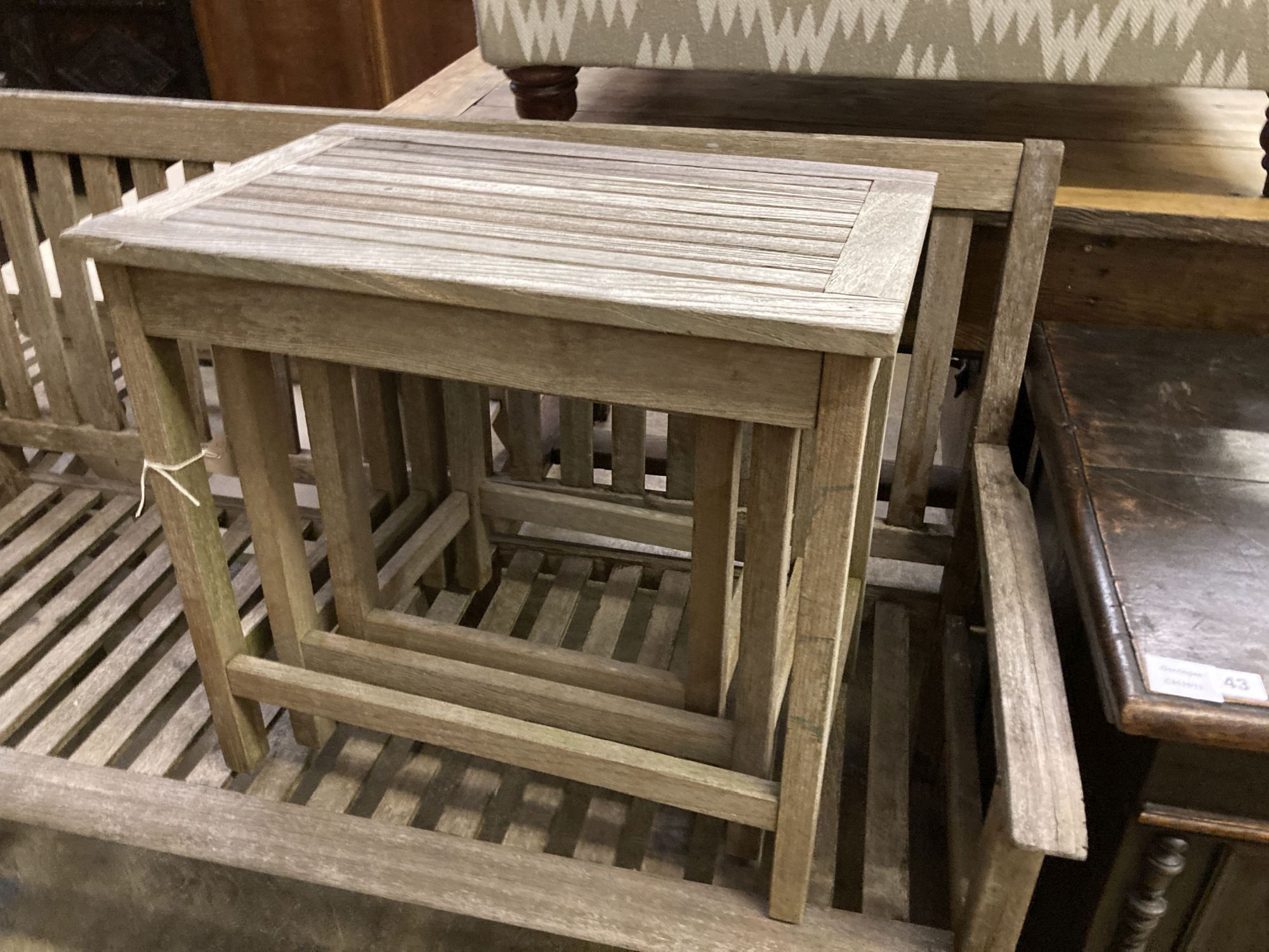 A weathered teak garden bench, length 129cm together with a teak steamer chair and nest of three teak rectangular garden tables